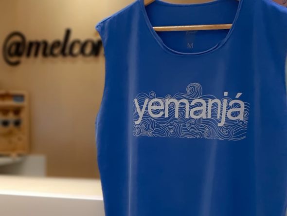 Camisa Yemanjá de R$ 71 por 49,70 na loja Mel com Dendê no Shopping Bela Vista. Doando 3 peças de roupa em bom estado, o produto sai por R$ 35,50. por Foto: Divulgação