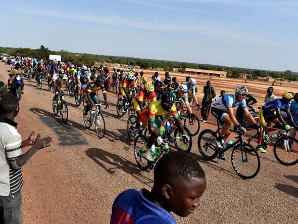 Ciclistas passam perto da aldeia de Yako, na fase 5 do tour de ciclismo do Burkina Faso. por ISSOUF SANOGO / AFP