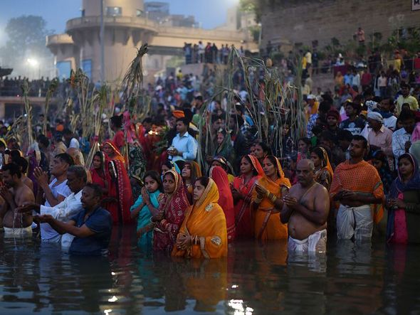 Devotos indianos participam de um ritual de adoração ao Deus Sol durante o Festival de Chhath, nas margens do rio Ganges em Varanasi.  por DOMINIQUE FAGET / AFP