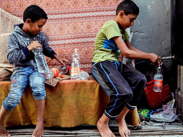 Meninos palestinos coletam água em cisterna de um bairro pobre em Khan Yunis, no sul da faixa de Gaza. Estima-se que 97% da água potável local não apresente boas condições para o consumo humano.  por THOMAS COEX / AFP
