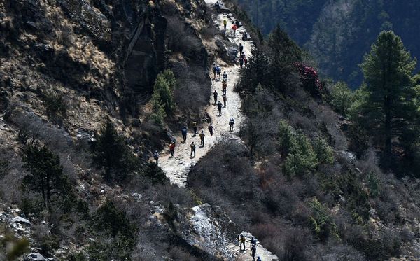 Alpinistas e moradores caminham numa das trilhas do Monte Everest, cerca de 140 km de Kathmandu, no Nepal.  por PRAKASH MATHEMA/AFP