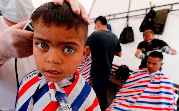 Migrantes venezuelanos cortam o cabelo numa brigada social do governo local, perto de um terminal de ônibus em Bogotá. por JOHN VIZCAINO / AFP