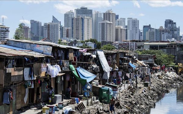 Favela em Manilla tendo ao fundo os prédios do distrito financeiro por Noel Celis/ AFP