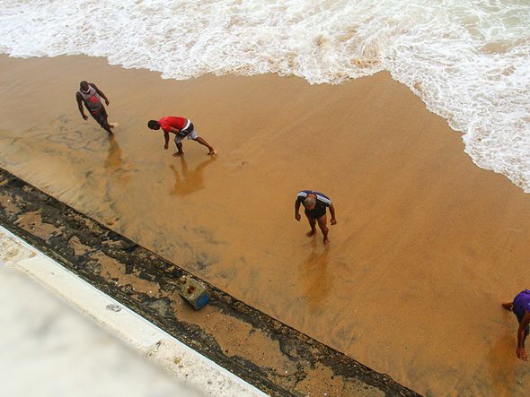 Homens catavam moedas, correntes e outros objetos trazidos pelo mar na Barra. por Tiago Caldas/CORREIO