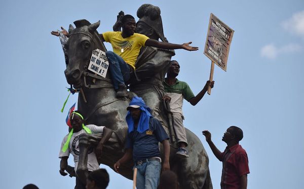 Manifestantes protestam na estátua de Jean Jacques Dessalines, em Porto Príncipe e exigem a responsabilização de políticos que alegadamente desperdiçaram bilhões de dólares no projeto PetroCaribe da Venezuela. por HECTOR RETAMAL / AFP