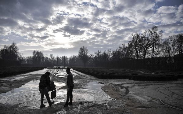 Migrantes limpam a margem do rio Parma em Colorno, Itália, após um período de fortes chuvas.  por MARCO BERTORELLO/AFP 