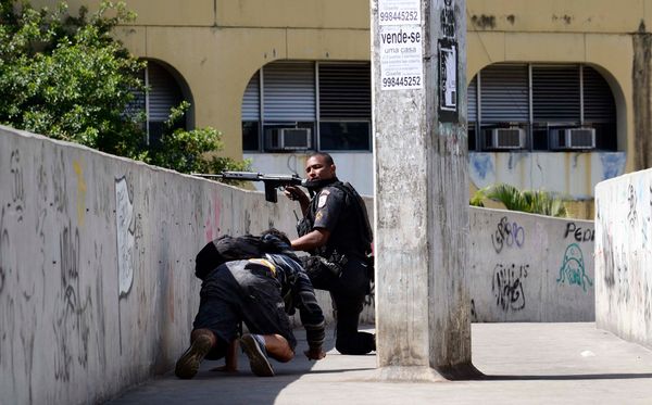 Policiais Militares se protegem durante tiroteio na favela da Rocinha, Rio de Janeiro, que fechou o tráfego de carros na região.
