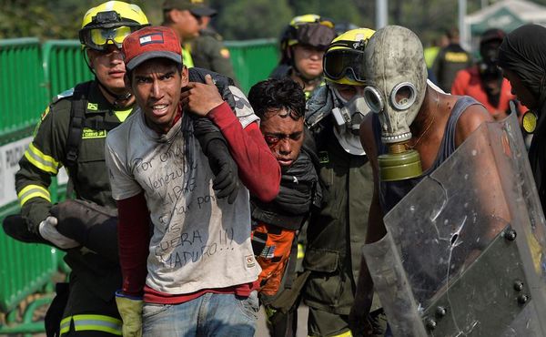 Um manifestante é socorrido na Ponte Internacional Simon Bolivar em Cúcuta, Colômbia, após ser ferido durante confrontos com as forças de segurança venezuelanas na fronteira de San Antonio del Táchira, na Venezuela. por LUIS ROBAYO / AFP
