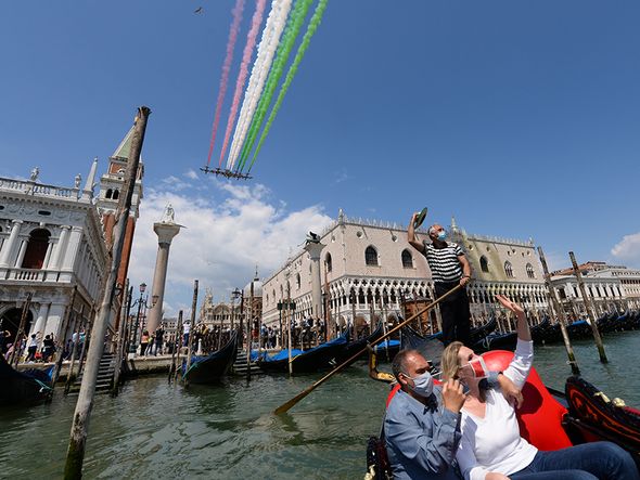 Em Veneza, na Itália, pessoas passeiam de gôndola e registram as acrobacias aéreas. por Andrea Pattaro/AFP