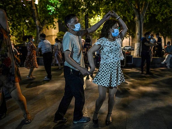 Pessoas dançam usando máscara em um parque próximo ao rio Yangtze, em Wuhan, cidade chinesa onde o coronavírus foi registrado pela primeira vez. por Hector Retamal/AFP