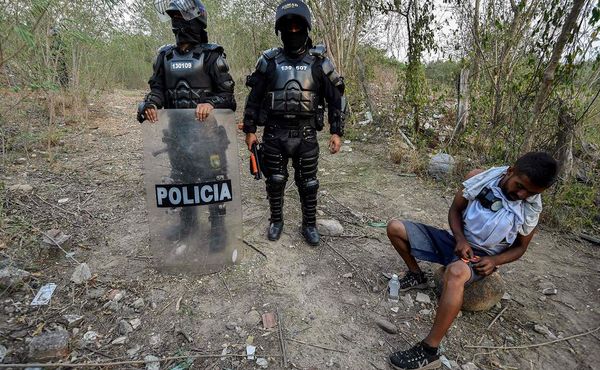 Agentes da polícia colombiana patrulham as margens do Rio Tachira, na fronteira com a Venezuela, à procura de possíveis desertores do exército venezuelano. São cerca de 326 militares que tentam atravessar a fronteira.  por LUIS ROBAYO / AFP