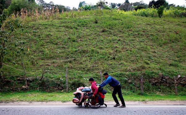 O migrante venezuelano Alexis Jefferson empurra a cadeira de rodas do pai Jose Agustin Lopez ao longo da estrada Cucuta e Pamplona, em Santander, Colômbia, em busca dos medicamentos que ele não poderia encontrar na Venezuela.  por SCHNEYDER MENDOZA / AFP