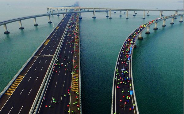 Competidores da Maratona Internacional de   Qingdao passam pela da Baía de Jiaozhou na   Província de Shandong na China.  por AFP