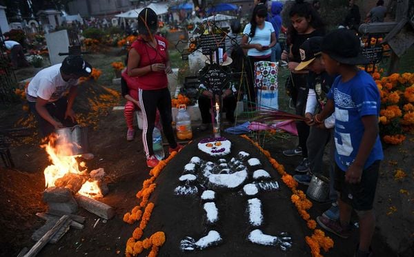 Famílias decoram os túmulos de seus entes queridos durante a celebração de Todos os Santos, em San Antonio Tecomitl, no México. por Pedro Pardo/AFP