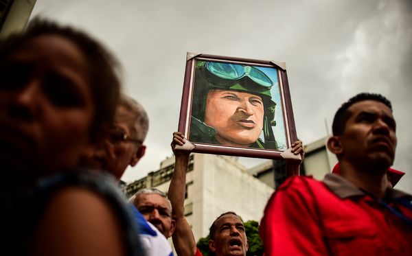 Manifestantes carregam imagem do ex-presidente Hugo Chaves, em Caracas, em manifestação a favor do governo da Venezuela. por Ronaldo Schemidt/ AFP