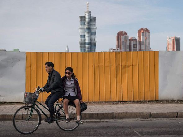 Ciclista em em frente às construções da 'Mirae Scientists Street' em Pyongyang, na Coéria do Sul. . por Ed Jones/AFP 