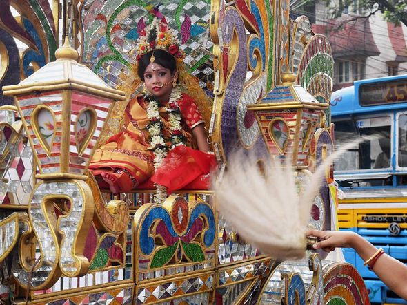 Garota vestida como a deusa Durga indo para um "pandal" – um lugar temporário de adoração durante o festival  Durga Puja.  por Dibyangshu Sarkar/AFP 