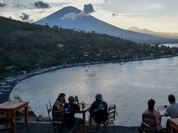 Turistas ao por sol apreciam a vista do Monte Agung às vesperas de uma anunciada erupção que já levou à evacuação de 144.000 pessoa.  por Bay Ismoyo/AFP 