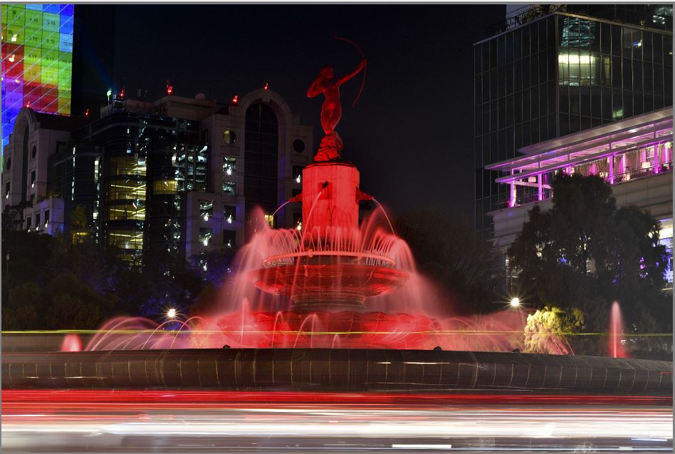 O monumento de "Diana La Cazadora" é iluminado de vermelho em comemoração ao Dia Mundial de Combate à AIDS na Cidade do México.  por YURI CORTEZ/AFP