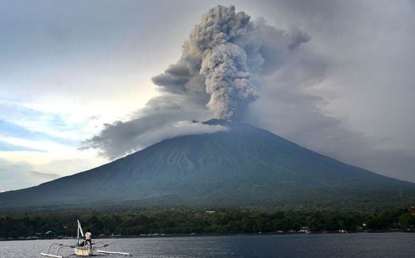 Pescador navega nos arredores do Monte Monte Agung cujo vulcão já entrou em erupção na Ilha de Bali. Autoridades indonésias estenderam o fechamento do Aeroporto Internacional por mais  mais um dia. por SONNY TUMBELAKA/AFP