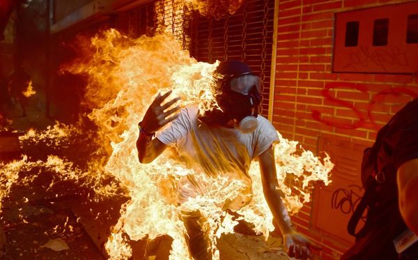 MAIO: Durante protesto contra o governo de Nicolas Maduro, na Venezuela, manifestante se incendeia após choque com a polícia. por RONALDO SCHEMIDT/AFP