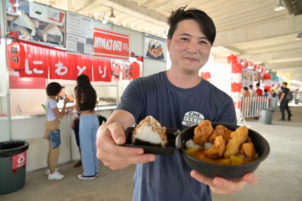 Rui segura onigiri de umeboshi e o chicken kare katsu, respectivamente