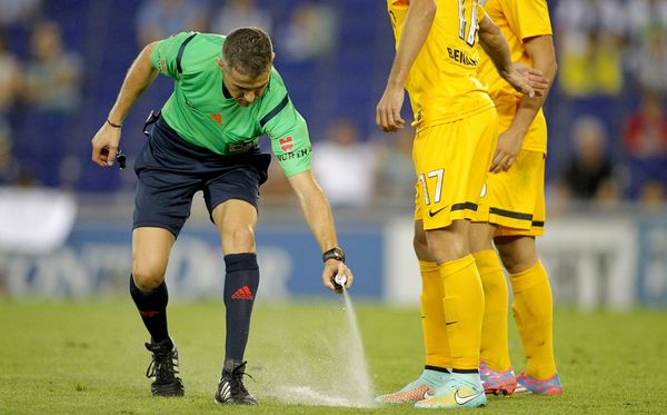 Árbitro utilizando o spray de barreira em jogo de futebol