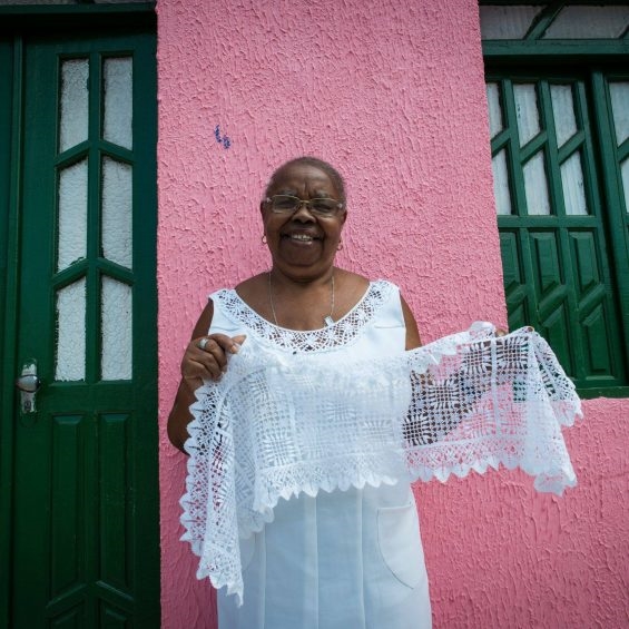 Maria do Carmo segura a renda de bilro