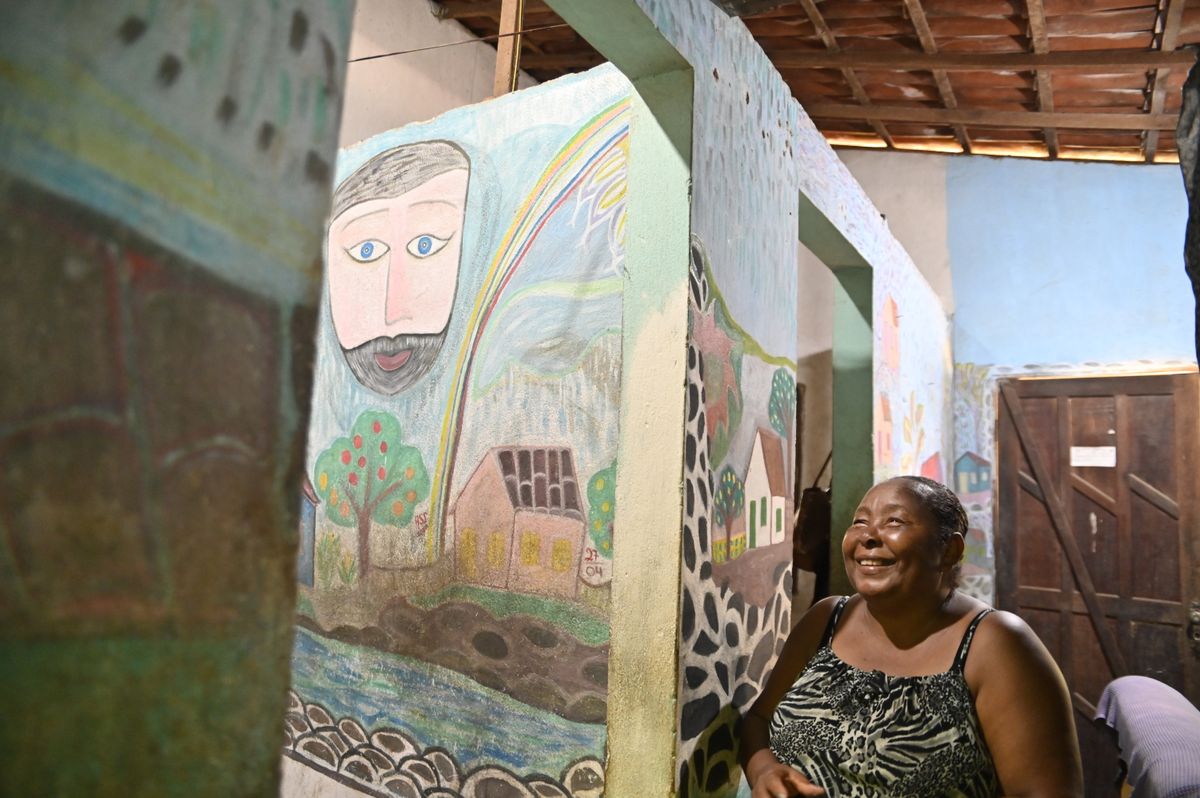 Antônia e seu primeiro painel com uma casa, arco-íris e um homem observando