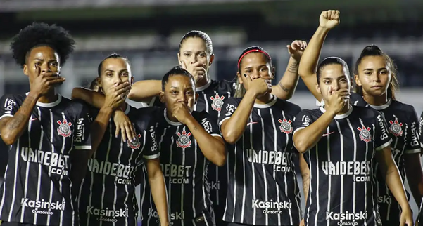 No Hino Nacional, as jogadoras do Corinthians, titulares e reservas, alinharam com uma das mãos na boca,