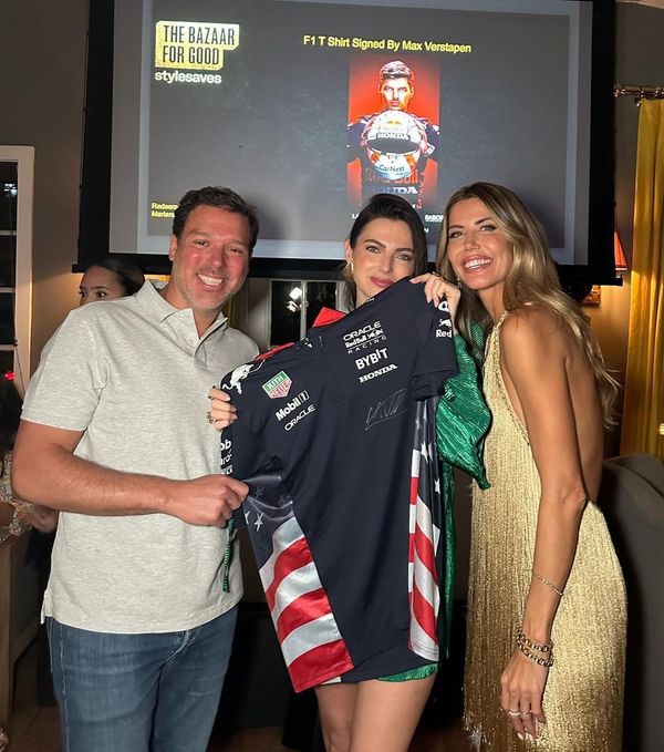 Kelly Piquet (ao centro) mostra a camisa de Verstappen que será leiloada