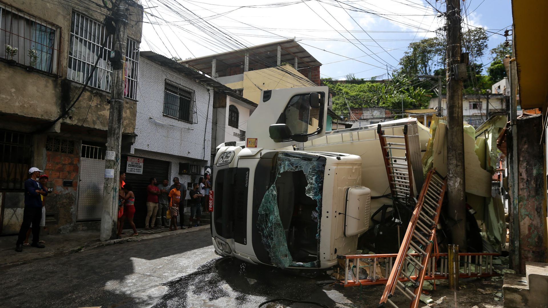 Imagem - Caminhão tomba na estrada do Lobato, destrói veículo estacionado e é saqueado por moradores