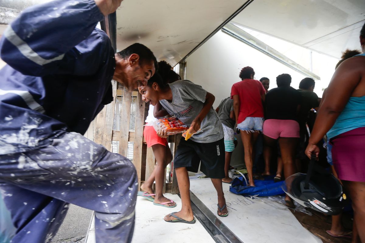 Dentro do caminhão tombado, moradores pegam carga de frios