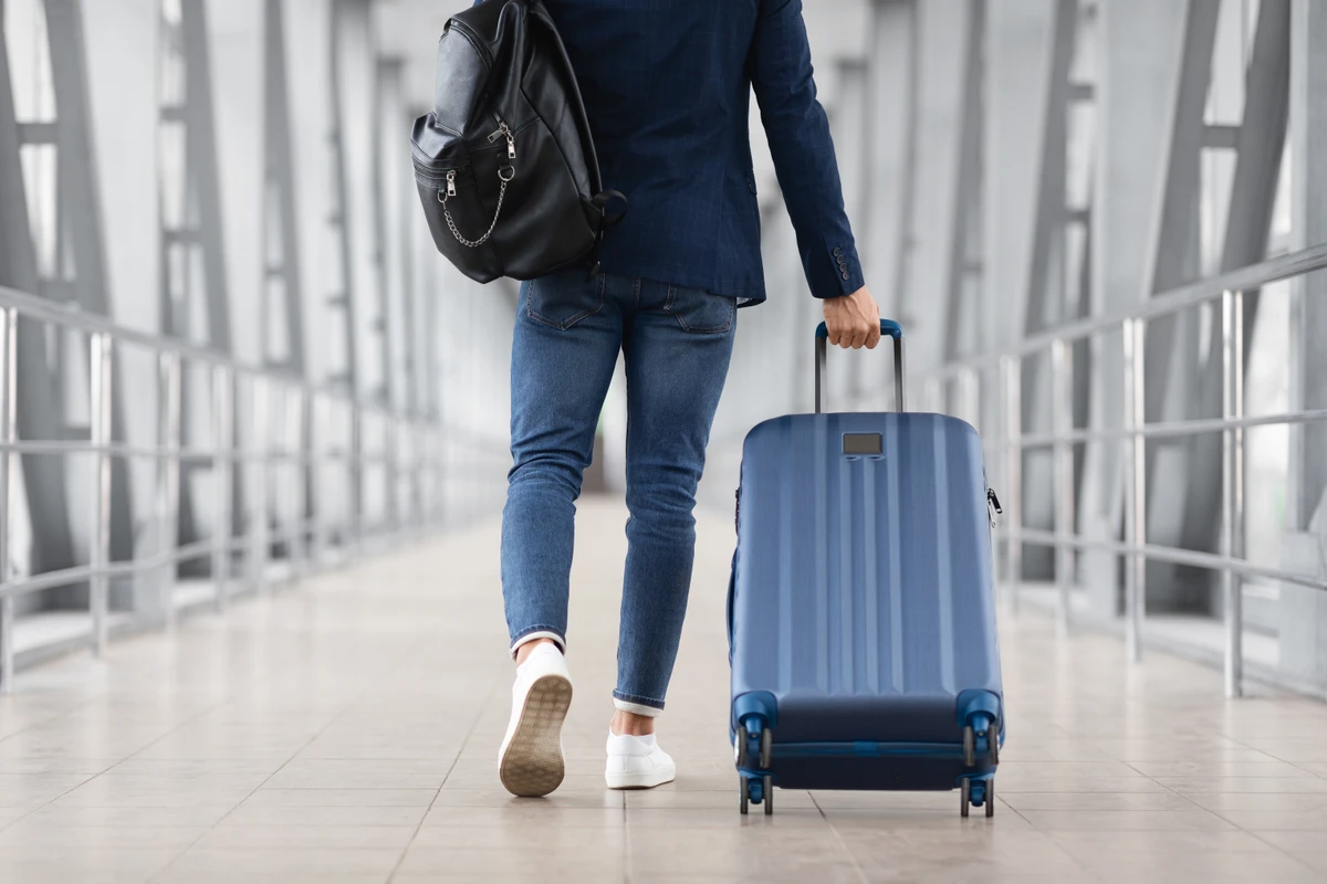 Pessoa arrastando mala de mão no aeroporto | Ilustrativa