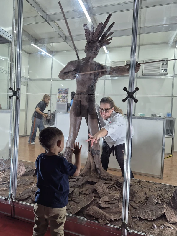 A chef Tati Benazzi, de São Paulo, brinca com criança diante de escultura de chocolate por Tharsila Prates/ CORREIO