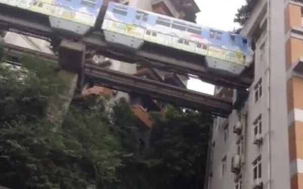 Trem passa por prédio em Chongqing por Reproduçaõ
