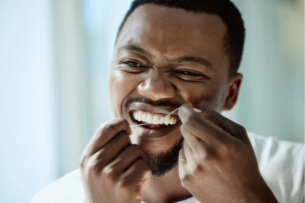 Homem passando fio dental