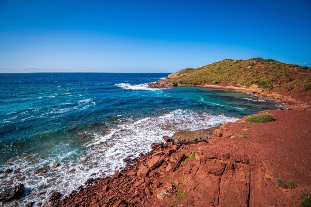 A Praia de Cavalleria se destaca pela areia avermelhada (Imagem: Ugo Burlini | Shutterstock)