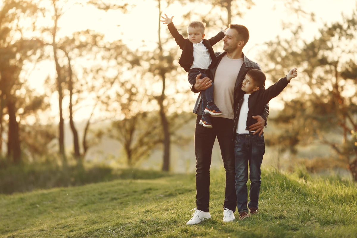 Family with cute little child. Father in a black jacket. Sunset background. por Reprodução | Freepik