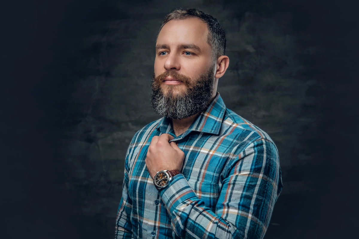 Portrait of serious middle age bearded male dressed in plaid flannel shirt over grey background. por Reprodução | Freepik