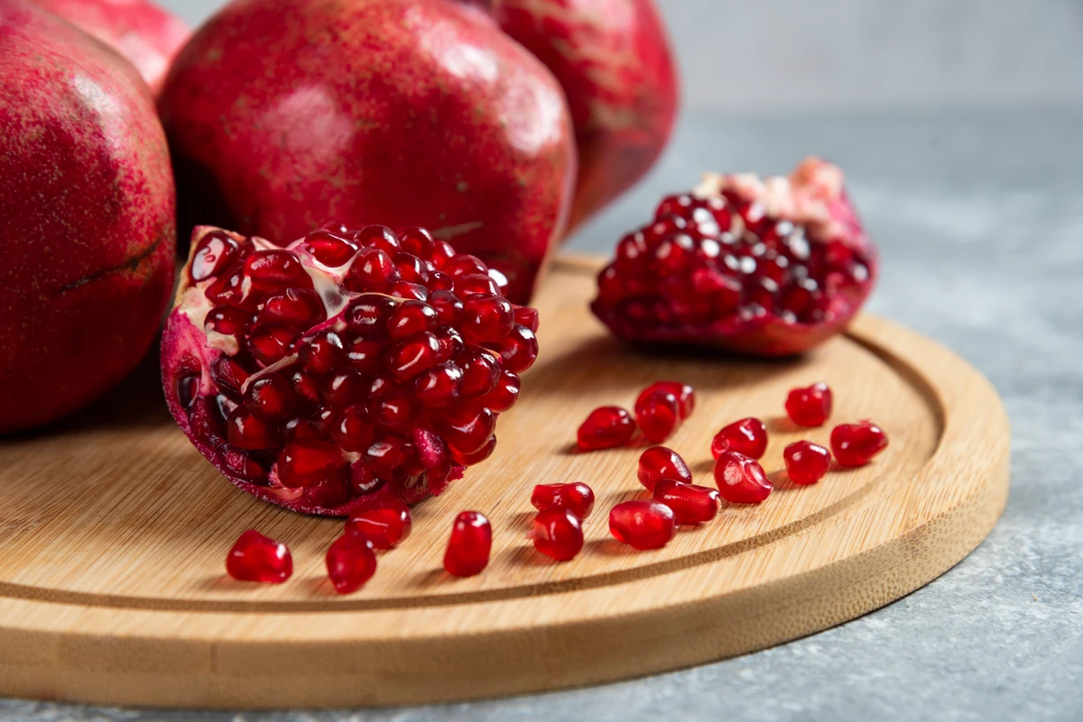 Sliced ripe pomegranate on a wooden board. High quality photo por Freepik