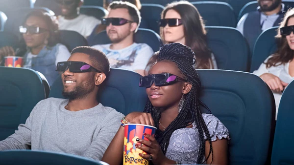 Ready to be entertained.Portrait of an attractive African couple sipping enjoying a 3D movie at the cinema 
