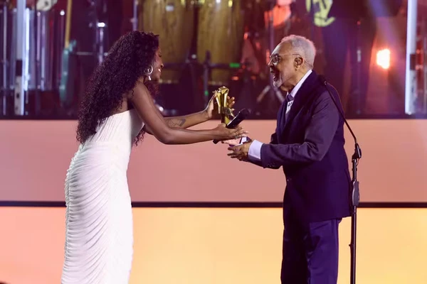 Gil recebe o troféu da apresentadora Kenya Sade por Manoela Mello/Divulgação