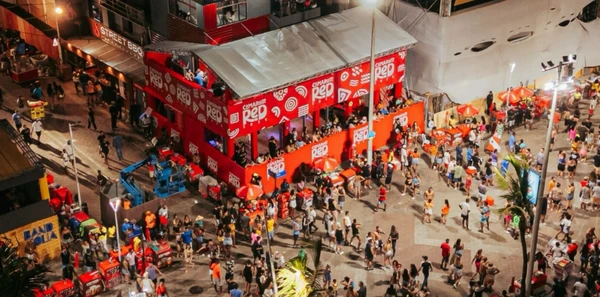 No coração do circuito Barra-Ondina, o camarote RED oferece uma vista única para a orla da Barra. O camarote conta com Full Open Bar Premium, com drinks assinados pelo Purgatório (presente na lista dos melhores bares do mundo em 2025), licor Royal Charlotte, fonte de Aperol Spritz da Casa Iryna, Whisky Jack Daniel's, Jägermeister, vodka, gin, refrigerante e água. A alimentação, no entanto, não está inclusa no valor do ingresso.As entradas vão de R$ 524,85 (terça-feira) a R$ R$ 743,35 (sábado). Onde comprar: Central do Carnaval. por Divulgação