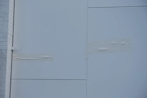 Fita branca cobrindo uma seção de um portão branco na casa de Rihanna por Reprodução