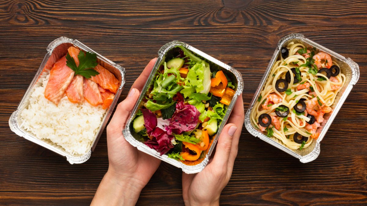 Montar as marmitas em camadas, priorizando molhos e grãos na base, ajuda a manter a umidade dos alimentos durante o reaquecimento