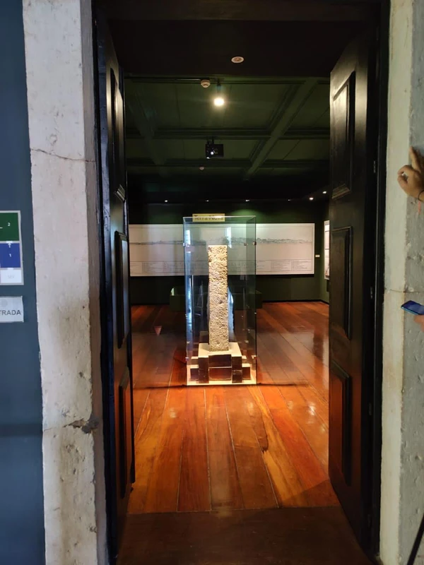 Marco de pedra com inscrição “T. do Tombo” preservado sob redoma após ser retirado do local de origem