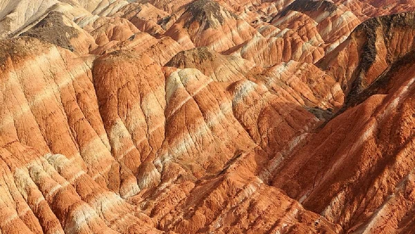 As rochas do Zhangye Colorful Hills foram depositadas em ambientes fluviais e lacustres no Cretáceo Inferior, antes de serem dobradas e expostas por Terry Wu / Wikimedia Commons