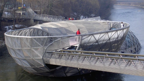 A Murinsel, em Graz, combina passarela, ilha artificial e pavilhão em uma estrutura curva e fechada que lembra uma ponte-anél por Wikimedia Commons