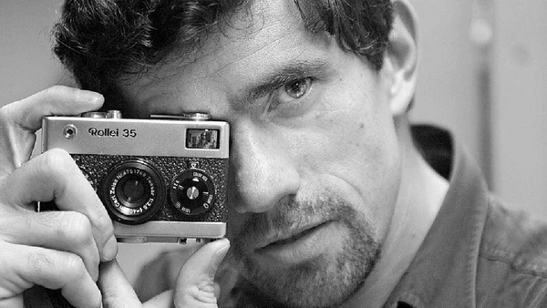 Antônio Gaudério segura sua câmera Rollei 35 em um autoretrato